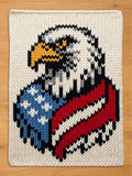 Chunky knit blanket featuring a patriotic American bald eagle design with red, white, and blue US flag patterns, displayed flat on a wooden surface.
