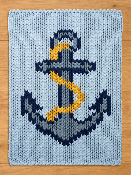 A light blue chunky knit blanket featuring a large, centered anchor design. The anchor is rendered in shades of dark navy blue, grey, and white, with a prominent yellow rope wrapped around the central shaft of the anchor structure.