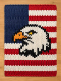 Thick-knit throw blanket featuring a bald eagle head design over an American flag pattern with red, white, and blue chunky yarn.