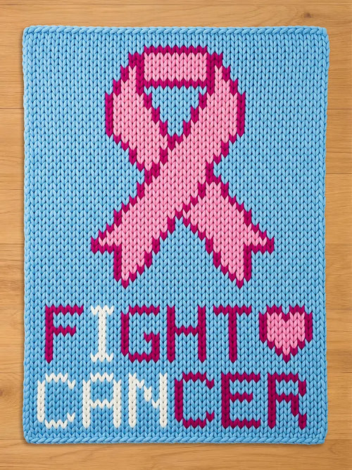 A knitted chunky blanket in light blue features a pink ribbon and the words "FIGHT CANCER" in white and pink. The heart symbol is pink. The design is a statement of support and awareness.