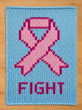 A knitted blanket in light blue features a pink ribbon design, a symbol of support. The word "FIGHT" is displayed in pink letters below the ribbon. The item is made of a textured, knitted material.