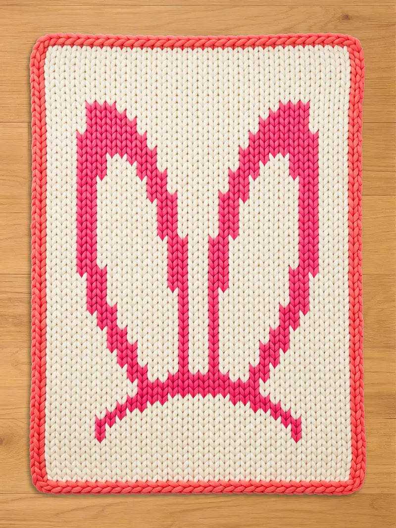 Chunky knit blanket featuring a pink bunny ears pattern on a cream white background with a pink braided border.