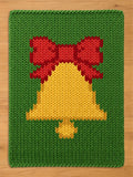 Chunky knit Christmas blanket in green featuring a large yellow holiday bell with a big red bow.