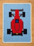 Chunky knit blanket featuring a red Formula 1 race car design on a light blue background with a white braided border.