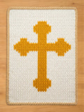 Chunky knit blanket in white featuring a large gold Orthodox cross pattern in the center with a braided beige border, displayed on a wooden floor.