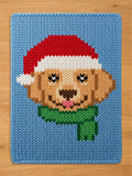Light blue chunky knit blanket featuring a woven design of a Golden Retriever wearing a red Santa hat and green scarf