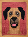 Chunky knit blanket featuring a woven portrait of a Great Dane dog face with black ears and a pink tongue against a rose pink background.
