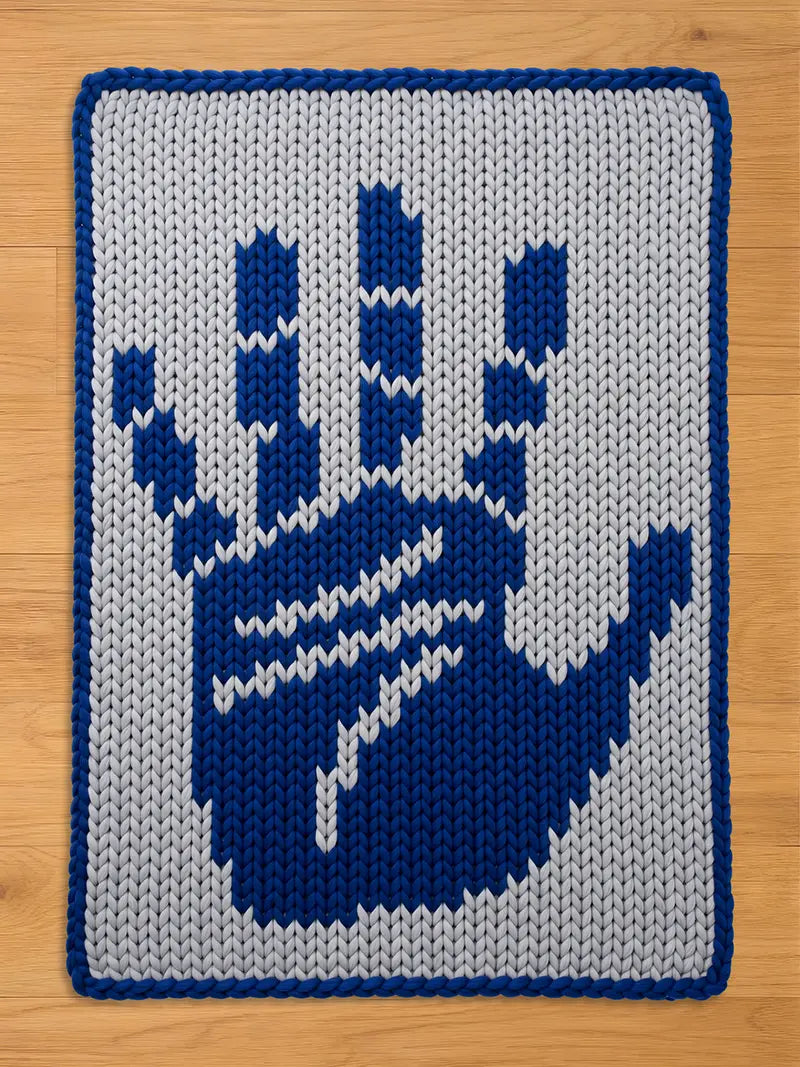 Chunky knit blanket featuring a large dark blue handprint design on a light grey background, finished with a matching dark blue border.