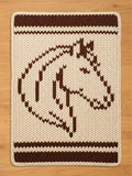 Cream and brown chunky knit blanket with a horse head design. Thick, cozy knitted throw blanket with equestrian motif and striped borders.