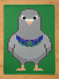 a chunky knit blanket with a pigeon design on a green background. The pigeon is gray with a blue, purple, and green collar. The bird has small black eyes and peach-colored feet. The background is a solid green color.