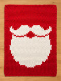 A rectangular knitted chunky blanket featuring a vibrant red background with a large, centered white graphic depicting a stylized mustache and beard. The knit pattern is uniform and chunky, creating a textured surface across the entire piece.