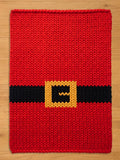 A rectangular chunky knit blanket featuring a vibrant red base with a horizontal black stripe across the center. A square yellow buckle design is centered on the black stripe, creating a pattern that resembles a Santa Claus suit.