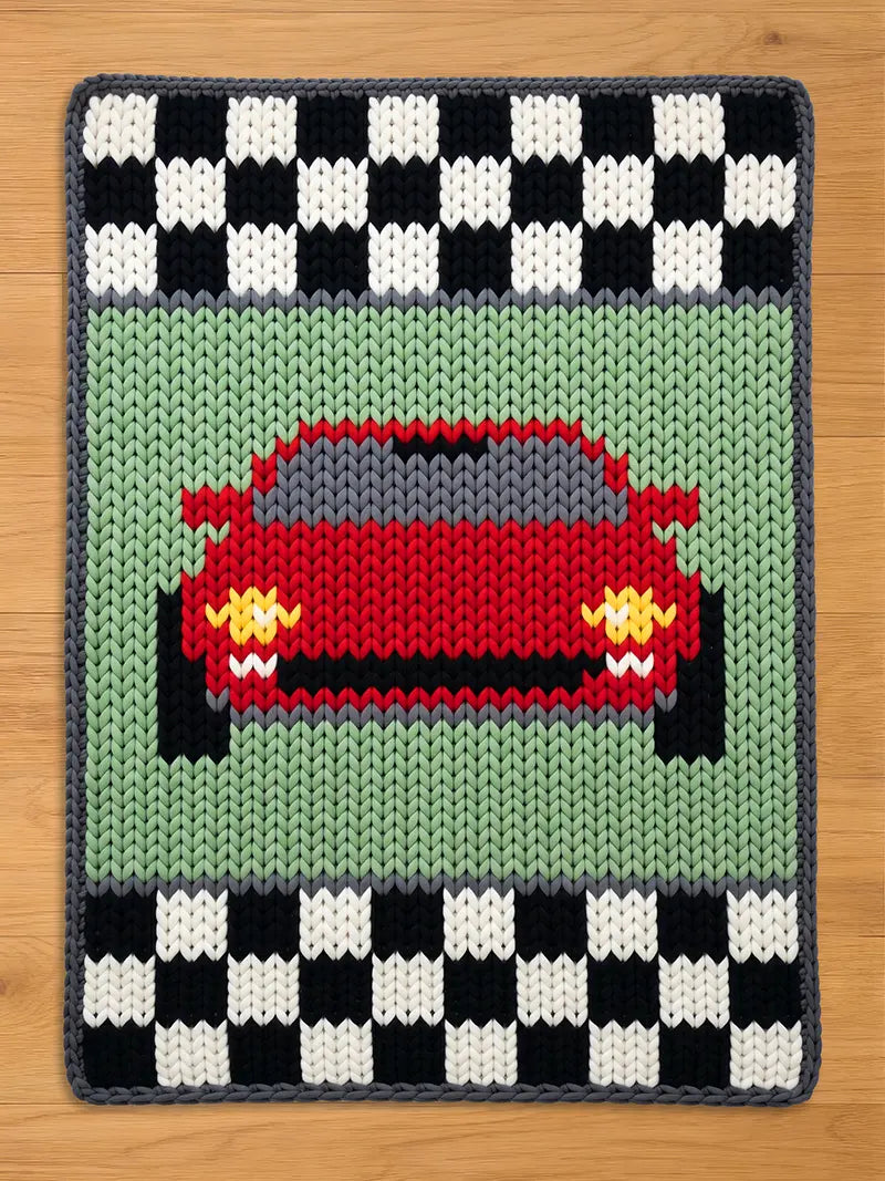 Chunky knit blanket featuring a front-facing red sports car on a light green background, bordered at the top and bottom by black and white racing checkerboard patterns