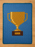 Chunky knit blanket featuring a large golden-yellow trophy cup design on a medium blue background